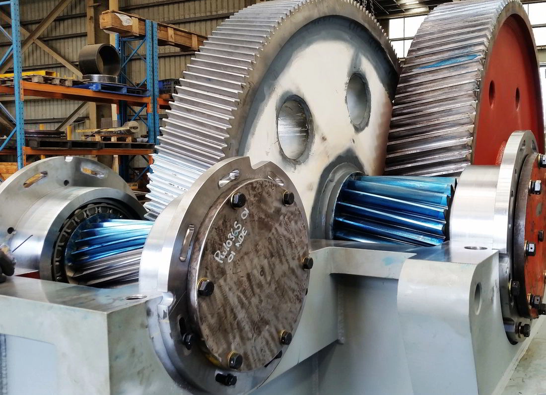 Overhauled heavy gearbox with large helical gears and machined shafts on the fitting floor
