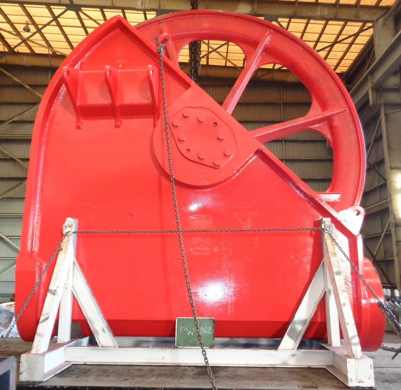 Freshly painted red dragline sheave wheel on stands in the industrial painting bay