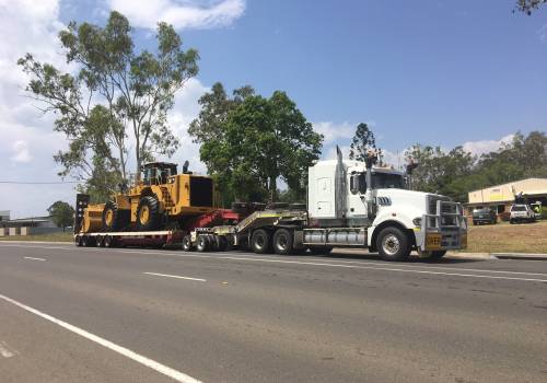 A Caterpillar wheel loader chained down on an ABC low-loader travelling the highway