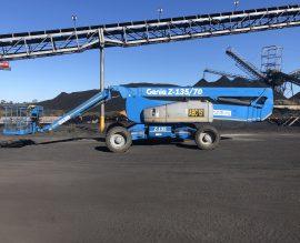 Genie Z-135/70 articulating boom lift working beneath conveyor gantries at a coal handling plant
