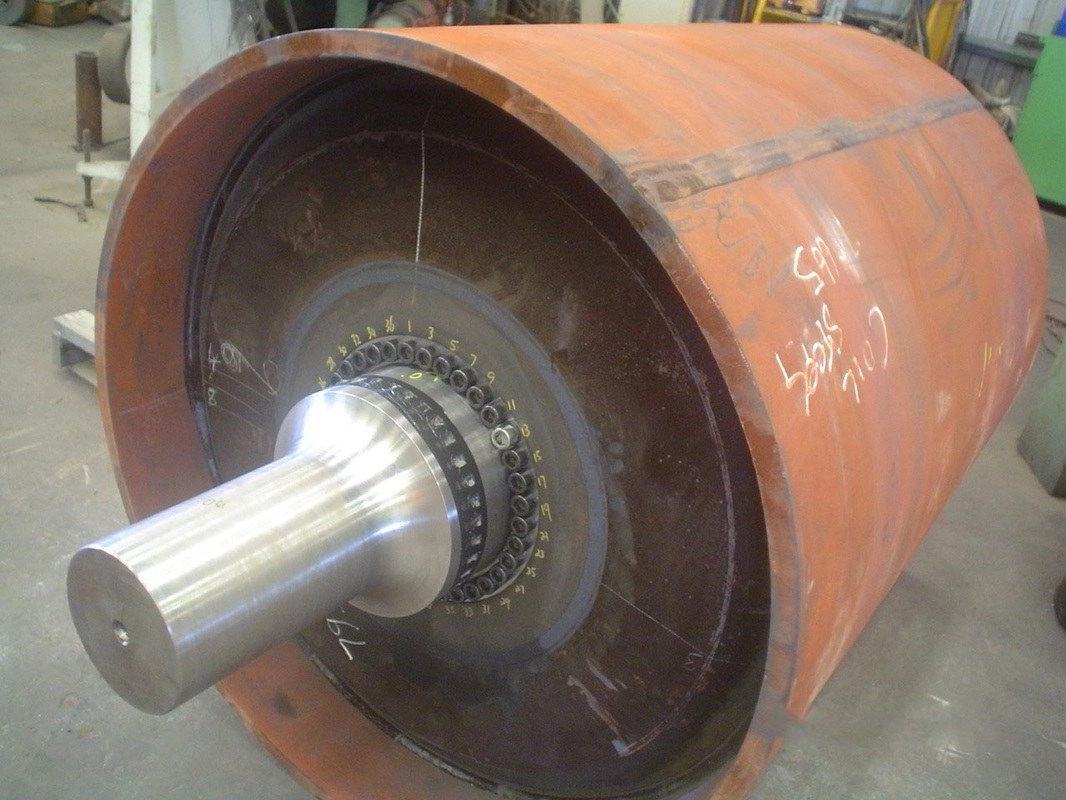 A large cylindrical drum on the workshop floor with its machined shaft and bolted hub fitted
