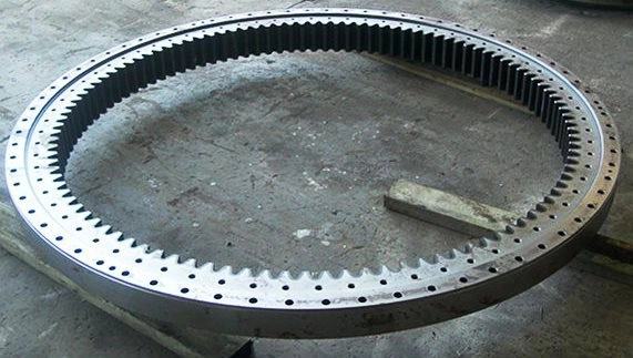 A large slew ring with internal gear teeth cut around its full circumference, resting on timbers