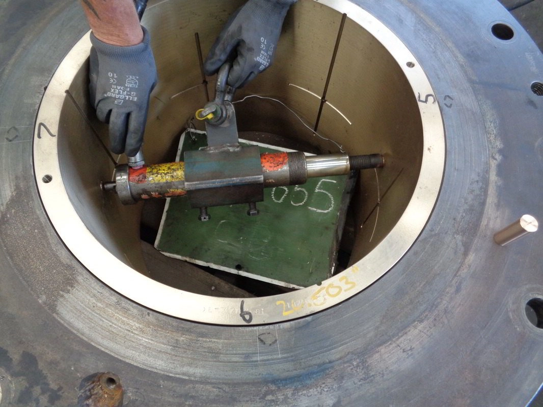Measurement tooling set up inside the bore of a large machined bearing housing during strip-down, datum points numbered in chalk around the bore face