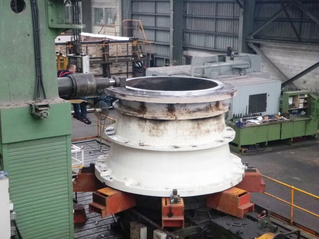 Large crusher shell component clamped in a CNC vertical borer mid-machining