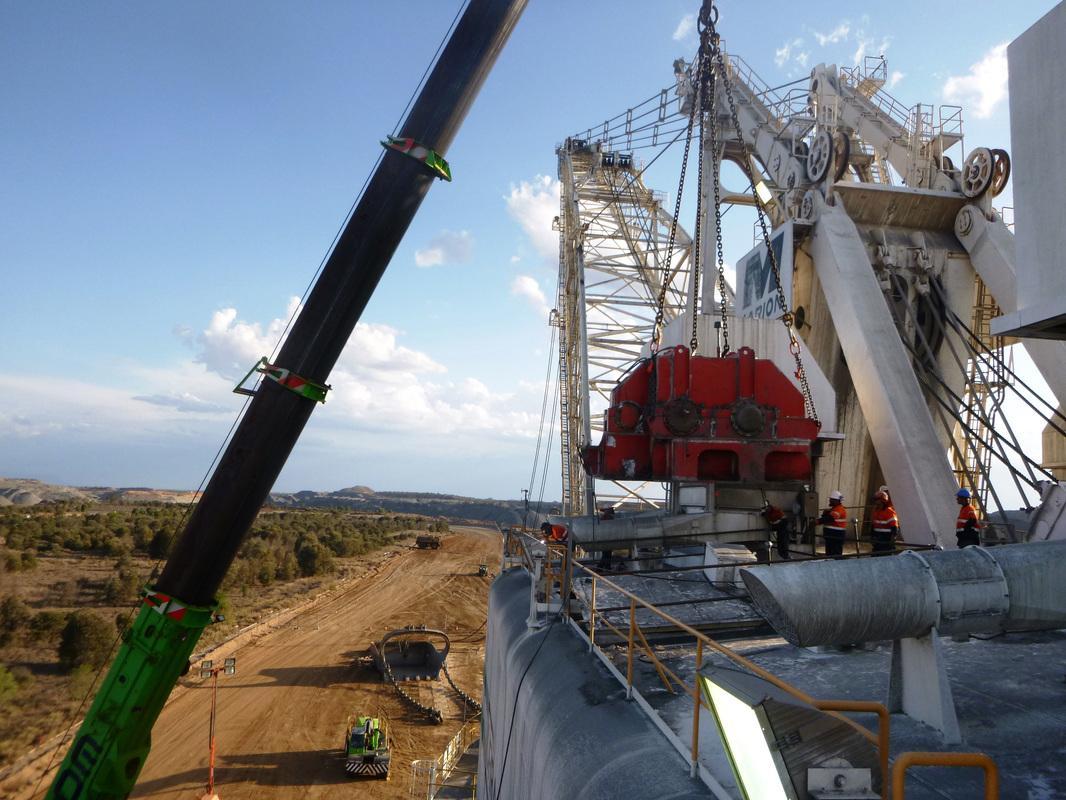 Crane lowering the red propel gear case onto the Marion 8750 dragline high above an open-cut pit, riggers watching from the machine deck